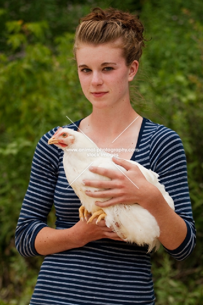 Young woman holding a White Rock hen chicken.