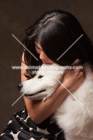 woman cuddling young Samoyed