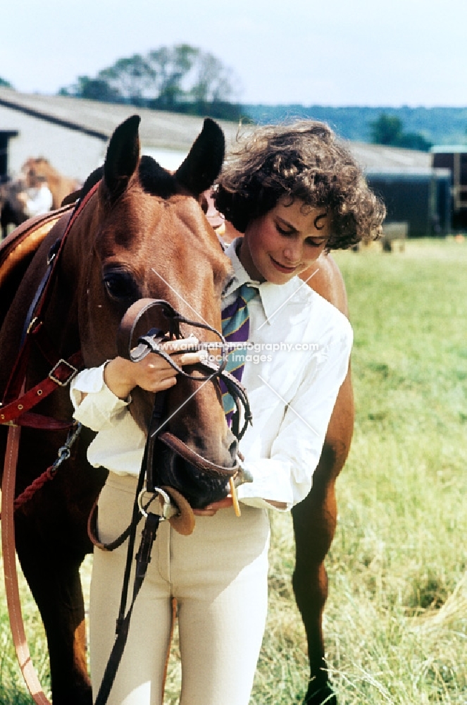 young girl putting bridle on her pony