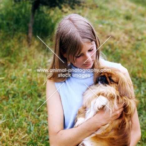 young woman cuddling a pekingese