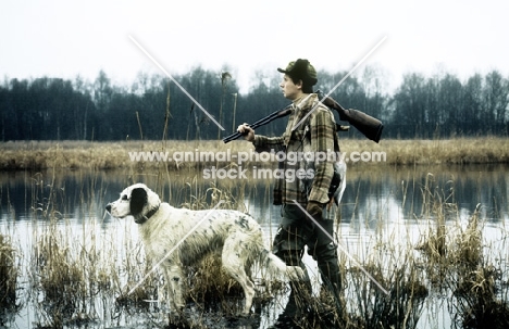 gundog walking in water at  riverside with hunter