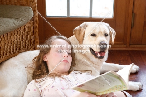 girl reading a book with Labrador