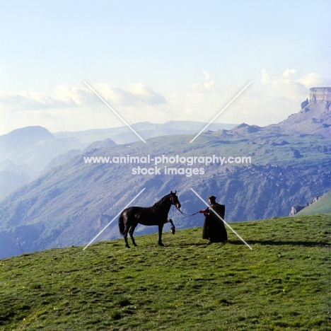 Arbich, Kabardine stallion held by cossack in Caucasus mountains