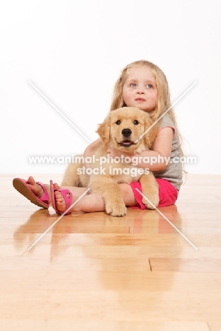girl and puppy on wooden floor