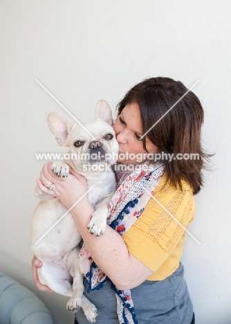 Fawn French Bulldog getting kissed by female owner.