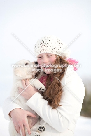 girl carrying Labrador puppy