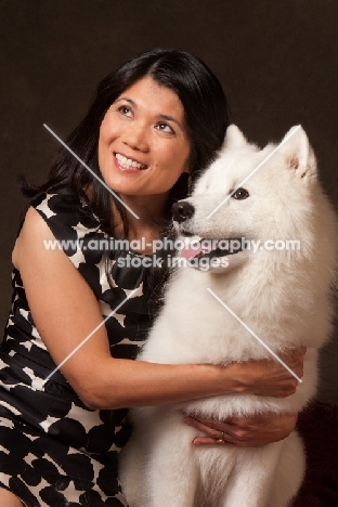 woman cuddling young Samoyed