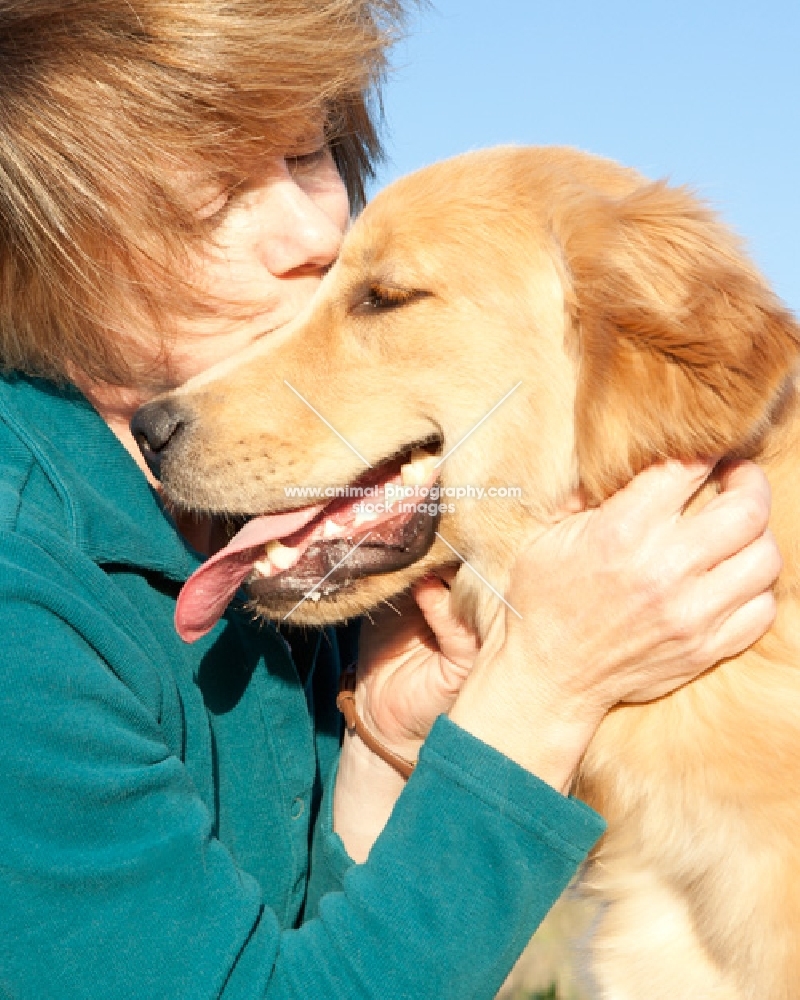 Golden Retriever being kissed by a woman