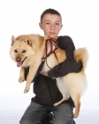 Picture of boy carrying Schipperke dog
