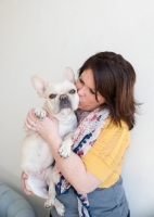 Picture of Fawn French Bulldog getting kissed by female owner.