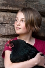 Picture of girl holding Black Australorp hen in old barn 