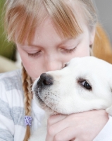 Picture of girl kissing her Labrador puppy