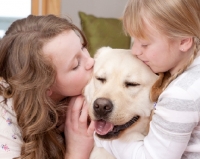 Picture of girls kissing a Labrador