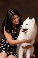 Picture of woman cuddling young Samoyed, looking at each other