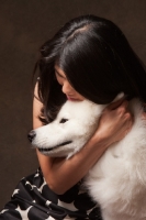 Picture of woman cuddling young Samoyed