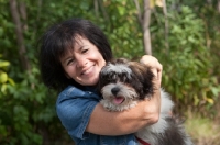 Picture of Woman hugging her Shih Tzu dog.