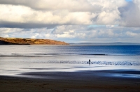 Picture of woman walking with 2 dogs on the beach at the Pembrokeshire coast in Wales