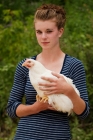 Picture of Young woman holding a White Rock hen chicken.